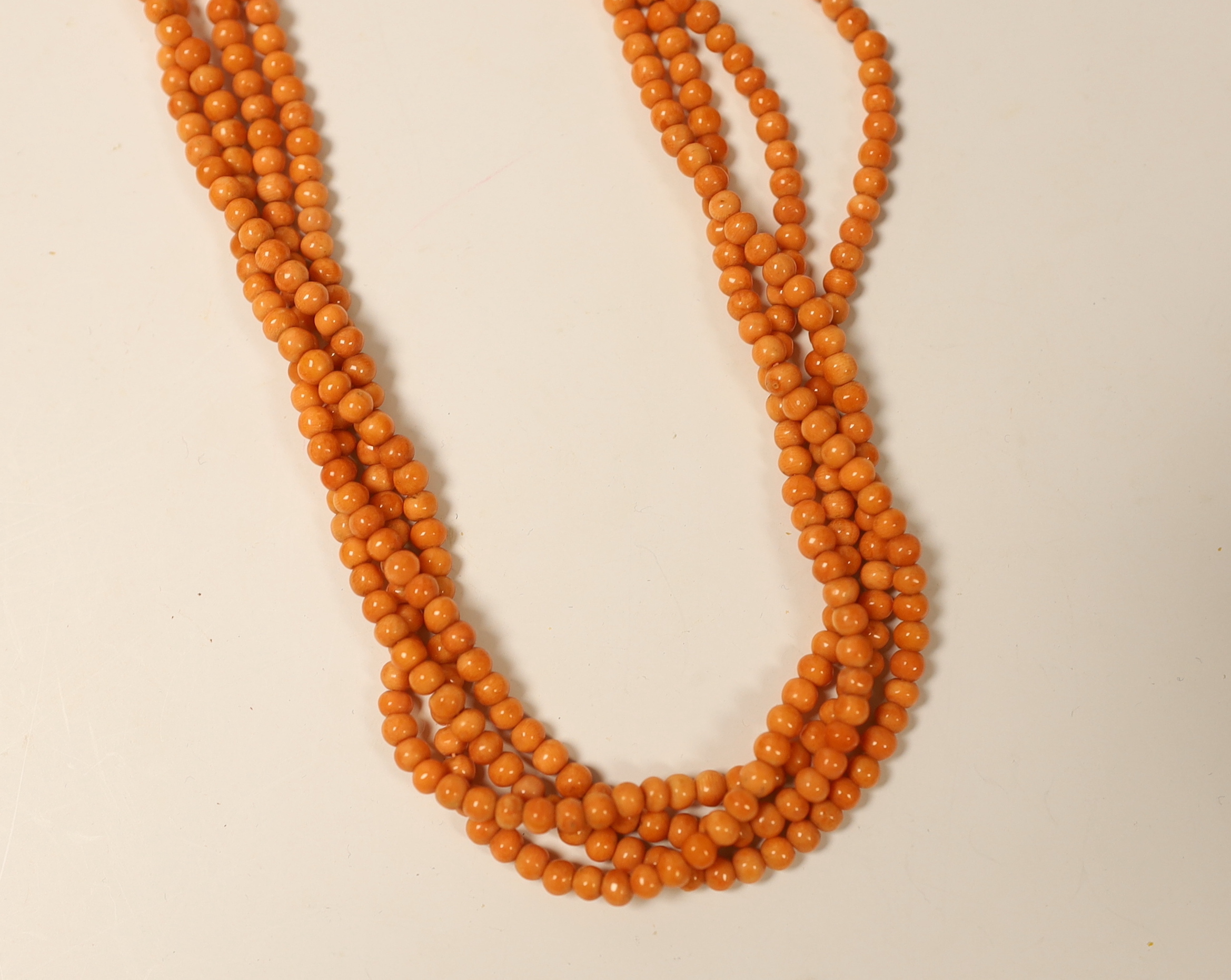 A quadruple strand coral bead necklace, with a gold plated clasp, 46cm.